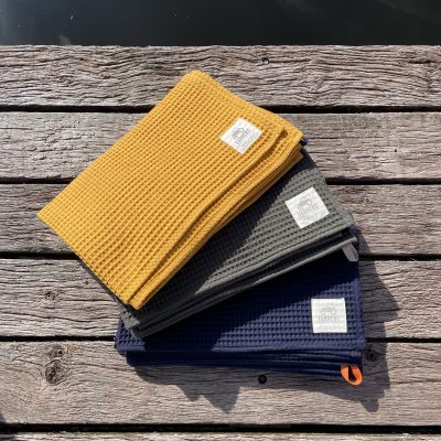 FARMERS' Swim & Sauna towel in 3 colours on wooden deck next to wild swimming pond