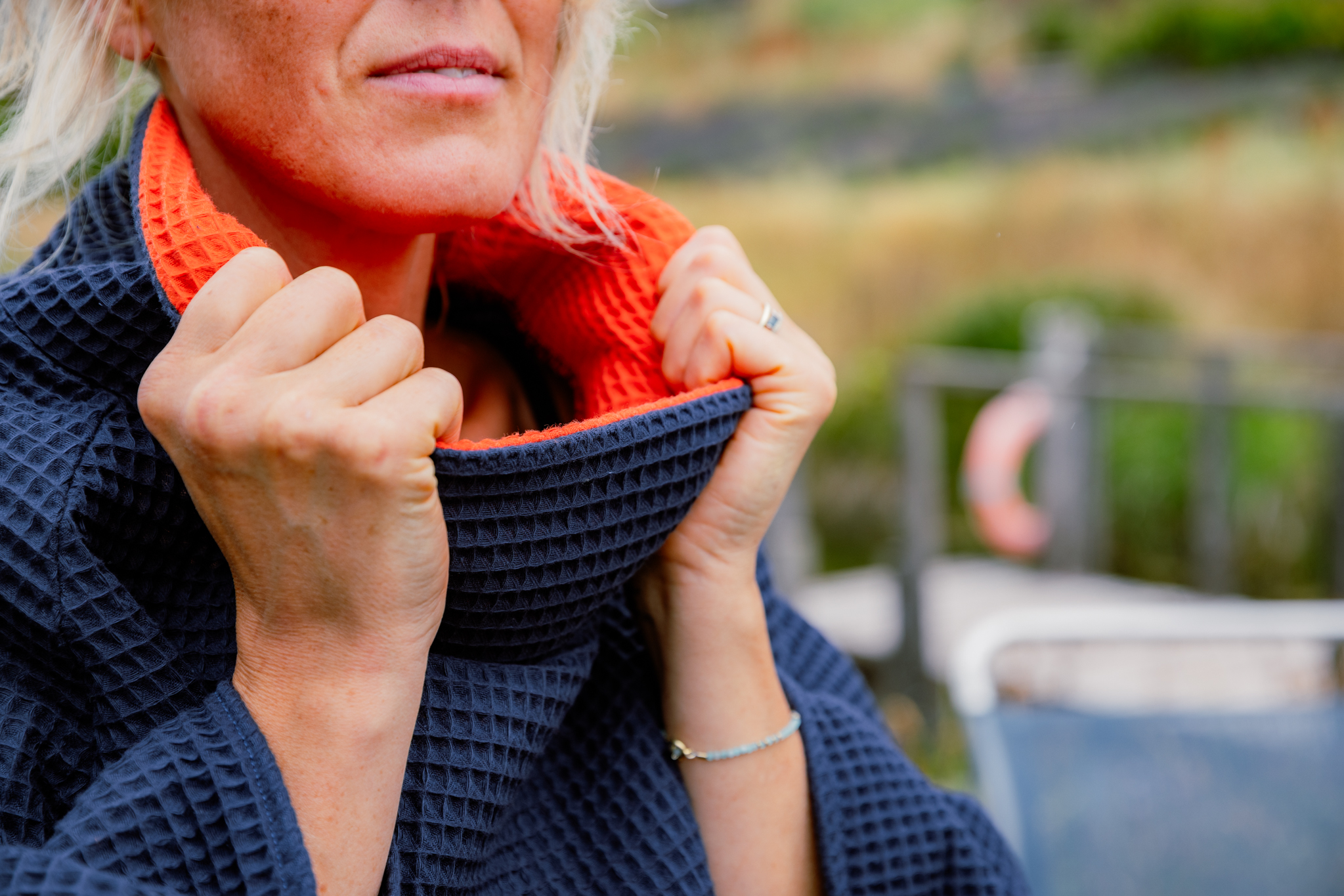 Close up of woman holding the collar of FARMERS' Waffle robe in navy, showing the orange inside of collar
