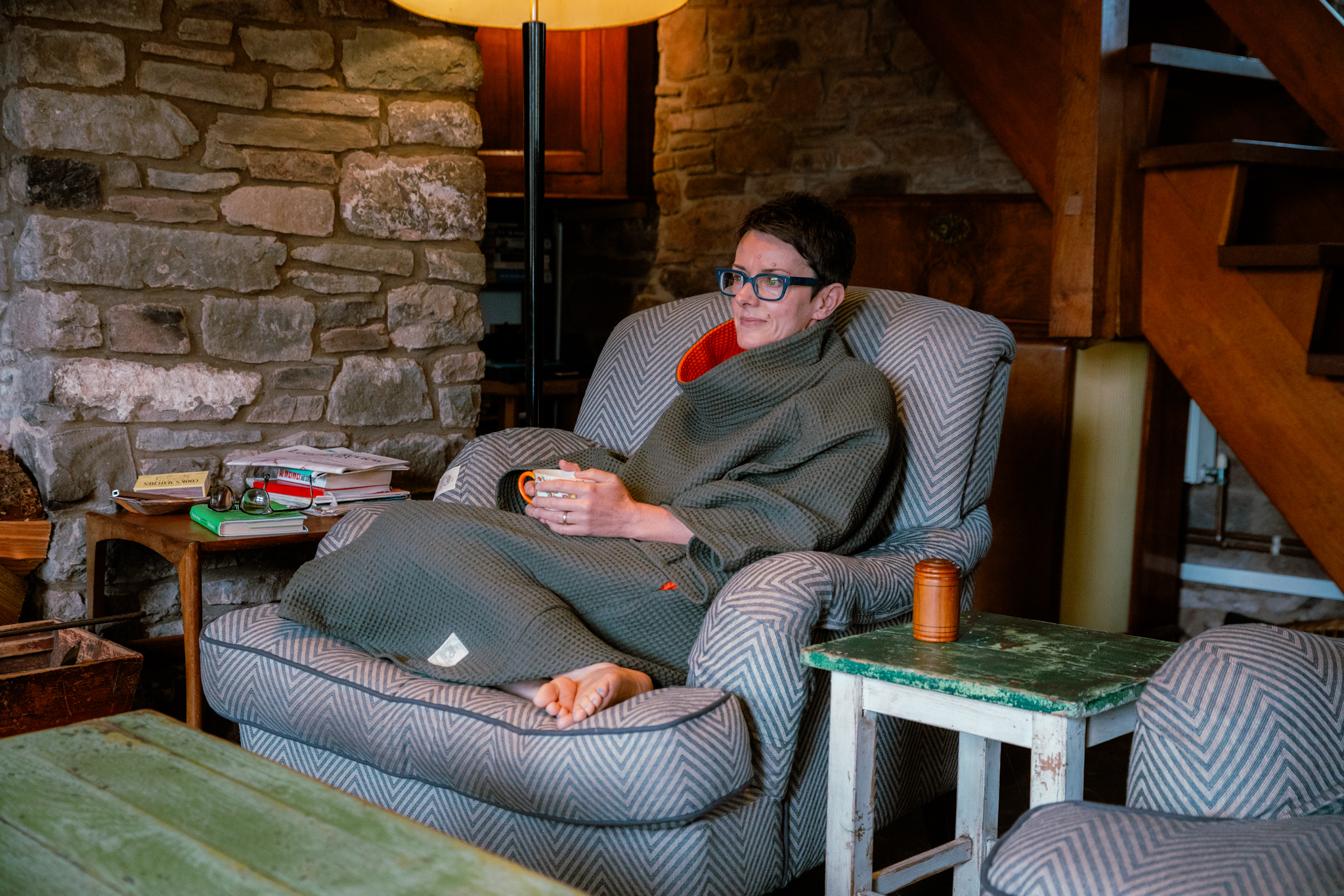 Woman sat in armchair wearing FARMERS' Waffle robe in army green holding tea cup